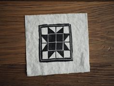 a piece of cloth with a black and white design on it sitting on top of a wooden table