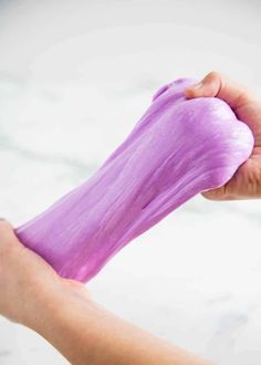 a person is drying their hair with purple dye on the tip of her finger and hand