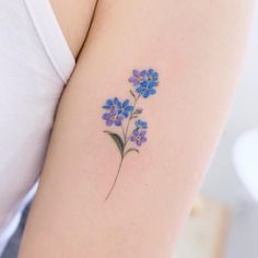 a small blue flower tattoo on the arm