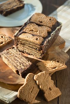 some cookies and cake are on a wooden cutting board next to plates with cut up cookies