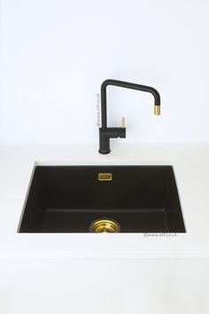 a black sink sitting under a faucet on top of a white counter