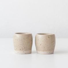 two white cups sitting side by side on a table