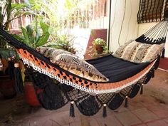 a black and orange hammock with zebra print pillows on the bottom, in front of a potted plant