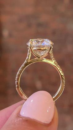 a person holding up a ring with a diamond in it's center and an oval stone on the side