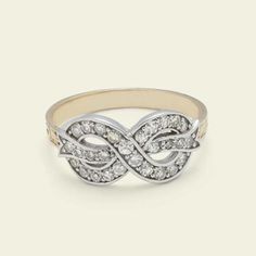 a white gold and diamond ring with an intertwined design on the band, set in 18k yellow gold