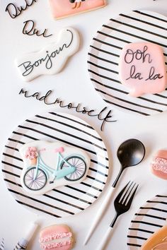 decorated cookies on plates with words written in english and french, along with forks and spoons