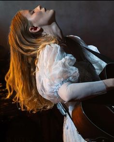 a woman with long hair holding a guitar