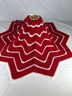 a red and white crocheted afghan sitting on top of a bed