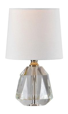 a crystal table lamp with a white shade on the base and a gold metal base