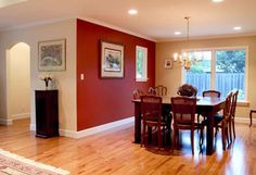 an empty dining room with red walls and hardwood floors