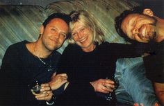 two men and a woman are posing for a photo with wine glasses in their hands