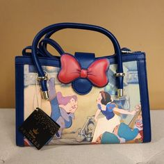 Enjoy Scenes From You Favorite Movie Snow White With This Sweet Handbag! Carry On Your Arm Or Wear As A Crossbody Bag. Make This The Perfect Gift For That Special Someone... Or Just Treat Yourself! * * * * Features * * * * * Height 7.5" * Width 3.5" * Length 11" * Dual Handle * Adjustable & Detachable Crossbody Strap * Gold Hardware * Flap With Magnetic Snap Closure * Faux Leather Exterior * Interior Is Blue Snow White Print Fabric * Inside Has 1 Zip Pocket, 1 Pouch * By Loungefly & Disney * New Cute Blue Bag For Disney Fan Events, Disney Style Shoulder Bag For Daily Use, Crossbody Shoulder Bag For Disney Trips, Themed Blue Bags For Gifts, Blue Rectangular Bag For Disney Trips, Blue Disney Bags For Gifts, Disney Blue Shoulder Bag For Travel, Disney Style Crossbody Bags For Disney Trips, Disney Purses And Handbags