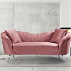 a pink couch sitting in front of a white wall