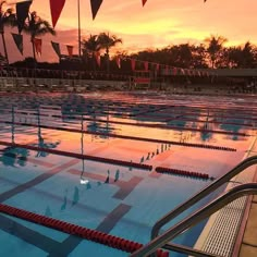 an empty swimming pool with red and blue flags in the background at sunset or dawn