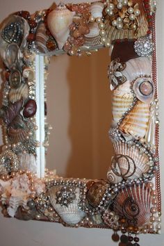 a mirror that has shells and pearls on it in the shape of a shell frame