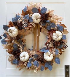 a wreath with white pumpkins and blue leaves