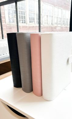 three different colored vases sitting on top of a white table next to a window