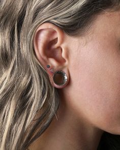 a close up of a person with ear piercings on their ears and wearing an earring