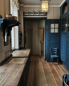 an old fashioned kitchen with blue doors and wooden floors