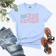 a t - shirt with the american flag on it next to some shoes and plants