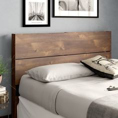 a bed with two pictures above it and a pillow on the headboard next to it