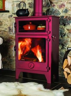 a pink stove in the middle of a room next to a chair and fire place