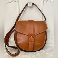 a brown leather purse sitting on top of a white bed