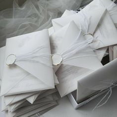 a bunch of white envelopes sitting on top of each other with ribbons tied around them