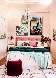 a bedroom with pink walls and paintings on the wall