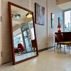 a large mirror sitting in the middle of a room next to a table and chairs