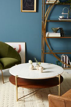 a living room with blue walls and white carpeted flooring, two green chairs and a round coffee table in the center