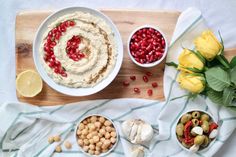 three bowls filled with food on top of a wooden table next to flowers and lemons