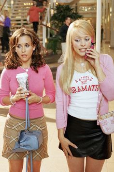 two young women standing next to each other talking on their cell phones and holding purses