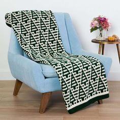 a blue chair with a black and white knitted blanket on it's back