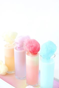 three different colored drinks sitting next to each other on a tray with marshmallows