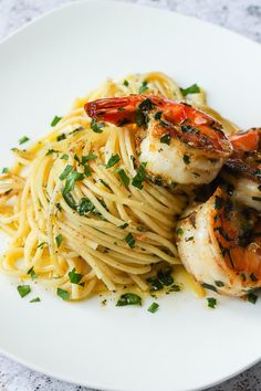 shrimp and pasta on a white plate with parsley