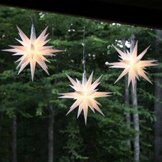 three paper stars hanging from strings in front of trees