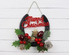 a christmas wreath hanging on the side of a white wall with pine cones and berries