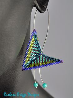 a pair of earrings with beaded designs hanging from it's earwires