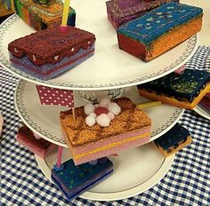 three tiered cake plate with cakes on it and candles in the middle, sitting on a checkered tablecloth