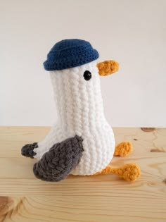 a crocheted bird with a blue hat on its head sitting on a wooden table