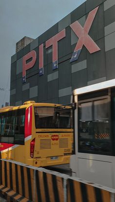 two yellow buses are parked in front of a building with the word pitt on it