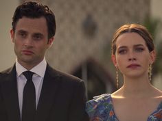 a man in a suit and tie standing next to a woman wearing a floral dress