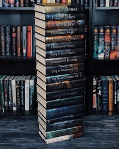 a stack of books sitting on top of a wooden table in front of a bookcase