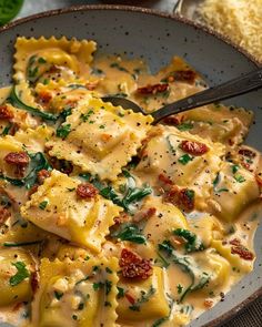 a bowl filled with pasta and spinach covered in sauce