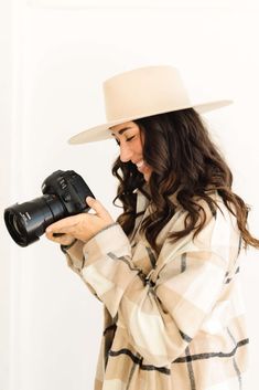 a woman wearing a hat and holding a camera