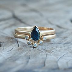 two gold rings with blue and white stones on them sitting on a piece of wood