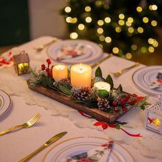 a table topped with plates and candles next to a christmas tree