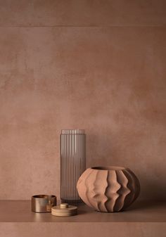 a vase sitting on top of a table next to two other items in front of a wall