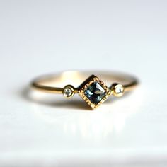 a close up of a ring on a white surface with a diamond in the middle